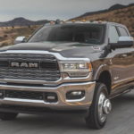 A grey 2020 Ram 3500 is driving down a two lane road after leaving a used Ram dealership.