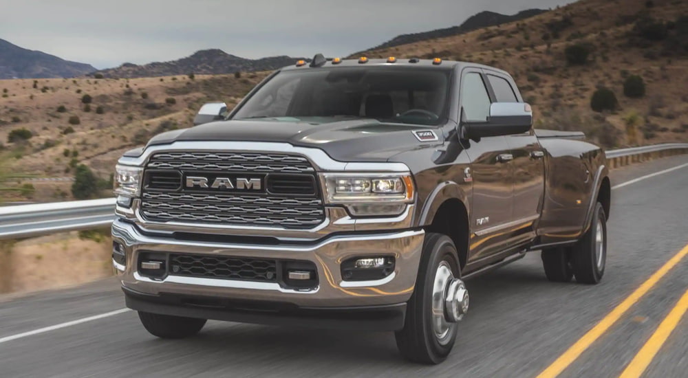 A grey 2020 Ram 3500 is driving down a two lane road after leaving a used Ram dealership.