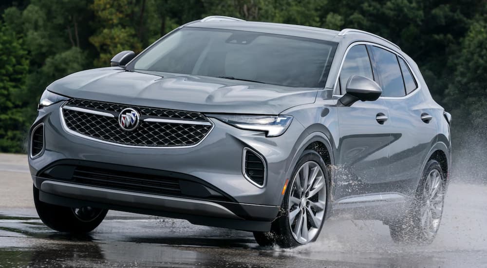 A grey 2021 Buick Envision is driving through a puddle.