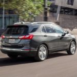 A 2021 Chevy Equinox is driving through a city after winning a 2021 Chevy Equinox vs 2021 Hyundai Santa Fe comparison.