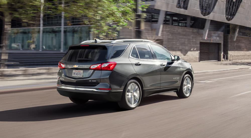 A 2021 Chevy Equinox is driving through a city after winning a 2021 Chevy Equinox vs 2021 Hyundai Santa Fe comparison.