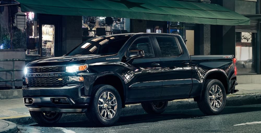 A black 2021 Chevy Silverado 1500 is parked on a city street at night.