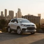 A white 2022 Chevy Trax is parked at the top of a hill overlooking the city.
