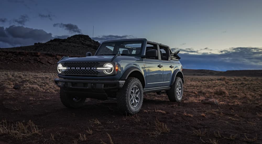A blue 2021 Ford Bronco is shown parked in a desert at dusk.