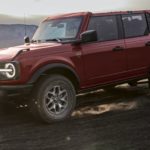 A red 2021 Ford Bronco is shown off-roading in a desert after wining a 2021 Ford Bronco vs 2021 Jeep Wrangler comparison.