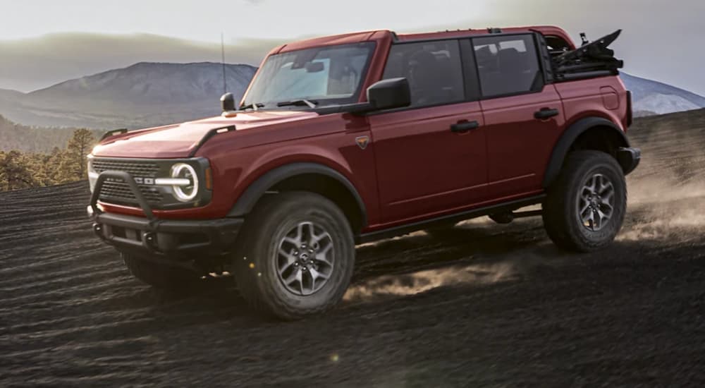 A red 2021 Ford Bronco is shown off-roading in a desert after wining a 2021 Ford Bronco vs 2021 Jeep Wrangler comparison.