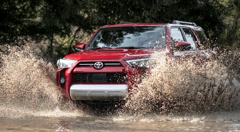 A red 2021 Toyota 4Runner is off-roading through a puddle.