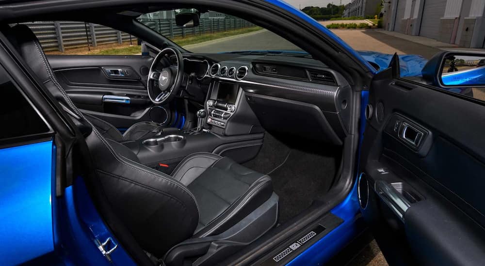 A bright blue 2021 Ford Mustang Mach 1 shows the interior, front seats, steering wheel, and infotainment system.