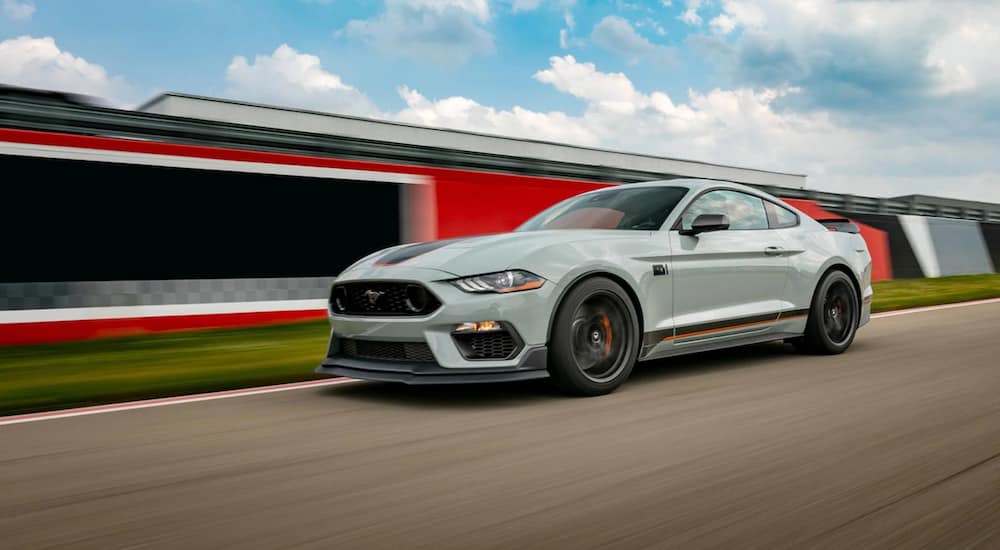 A pale green 2021 Ford Mustang Mach 1 is driving on a racetrack.