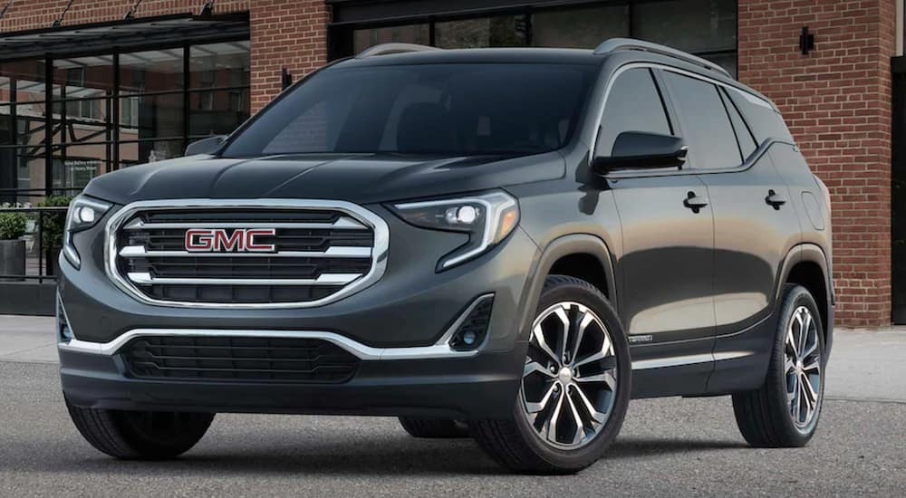 A grey 2021 GMC Terrain is shown parked in front of a brick building.
