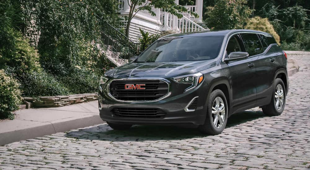 A green 2021 GMC Terrain is driving down a cobblestone road after winning a 2021 GMC Terrain vs 2021 Jeep Compass comparison.