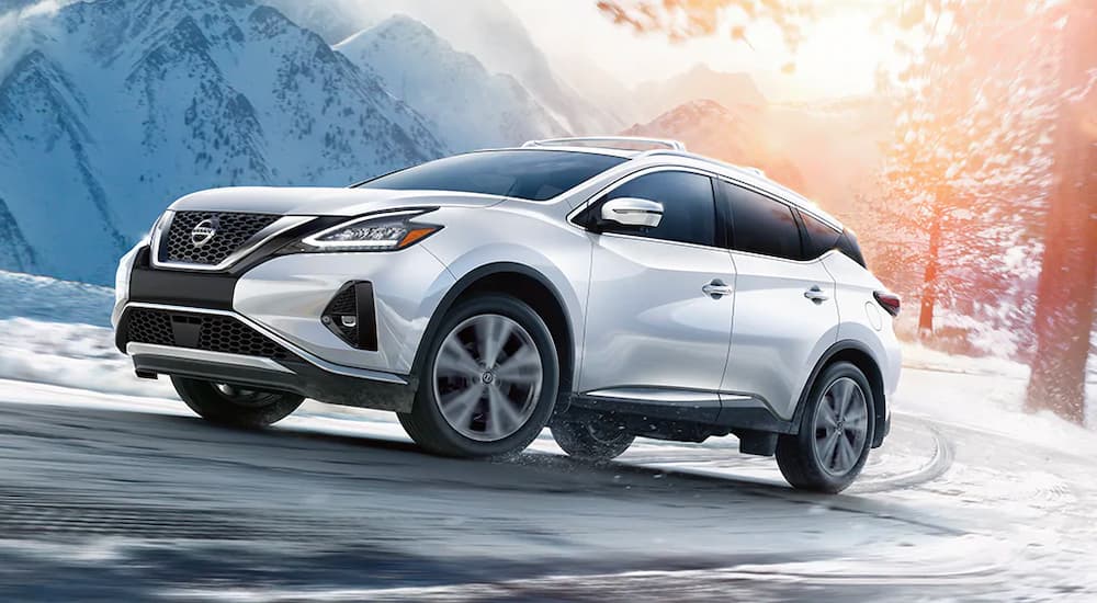 A white 2021 Nissan Murano is shown driving on a snowy road.