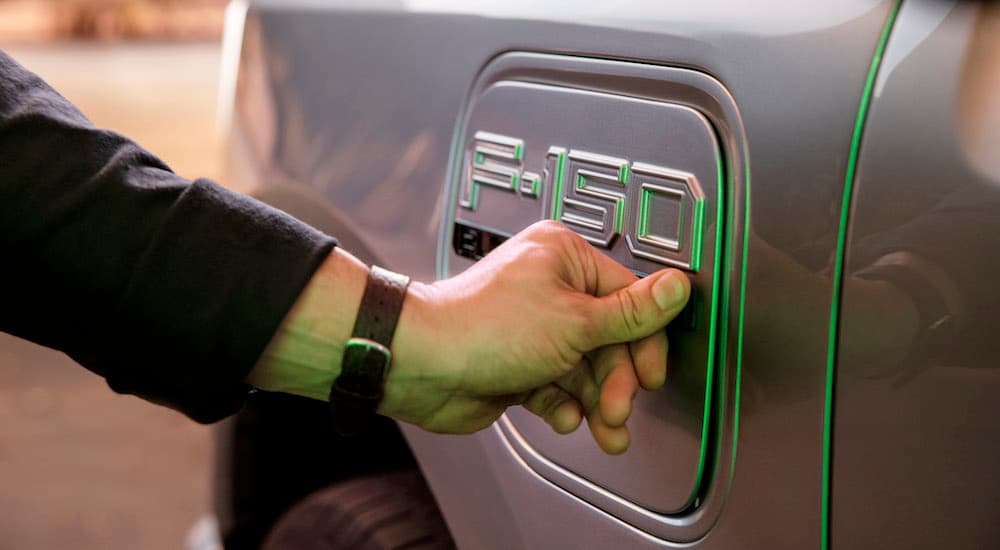A close up shows someone opening the charging door on a silver 2022 Ford F-150 Lightning.