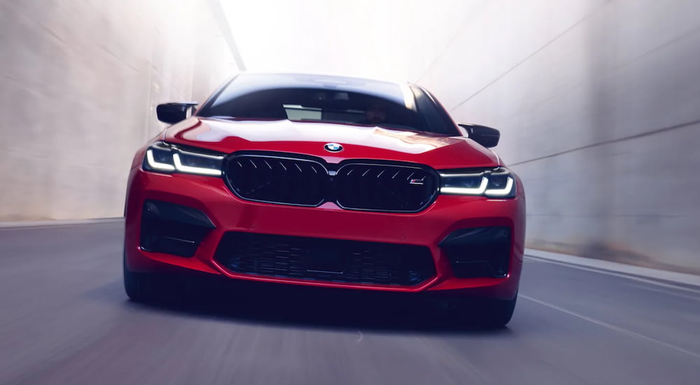 A red 2021 BMW M5 Sedan driving through a narrow tunnel. 