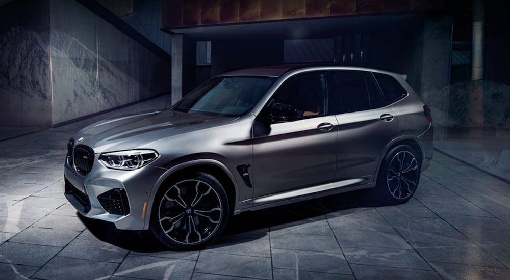 A silver 2021 BMW X3 M Series is parked in a modern garage.