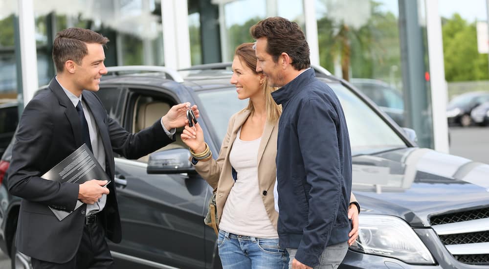 A salesman is passing a woman her new car keys.