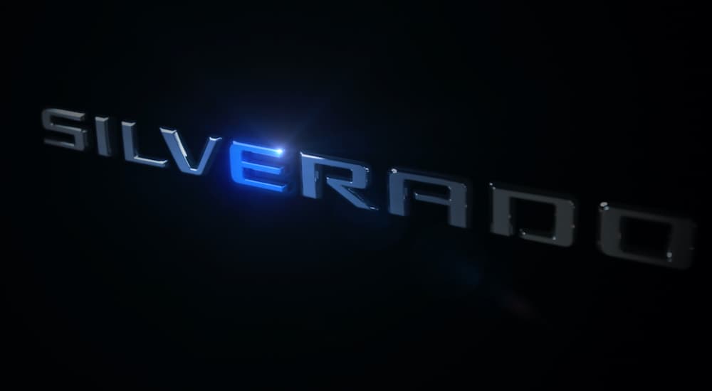 A close up shows the Silverado logo illuminated for the upcoming Chevy EV release.