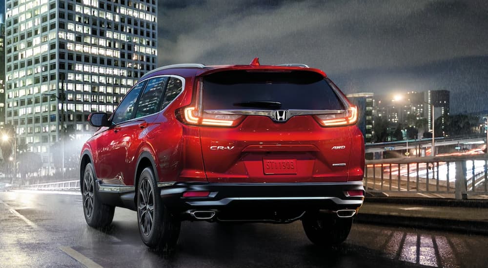 A red Honda CR-V 2021 Touring is shown from the back driving through a city.