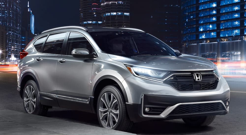 A silver 2021 Honda CR-V Touring is shown parked in a city at night.