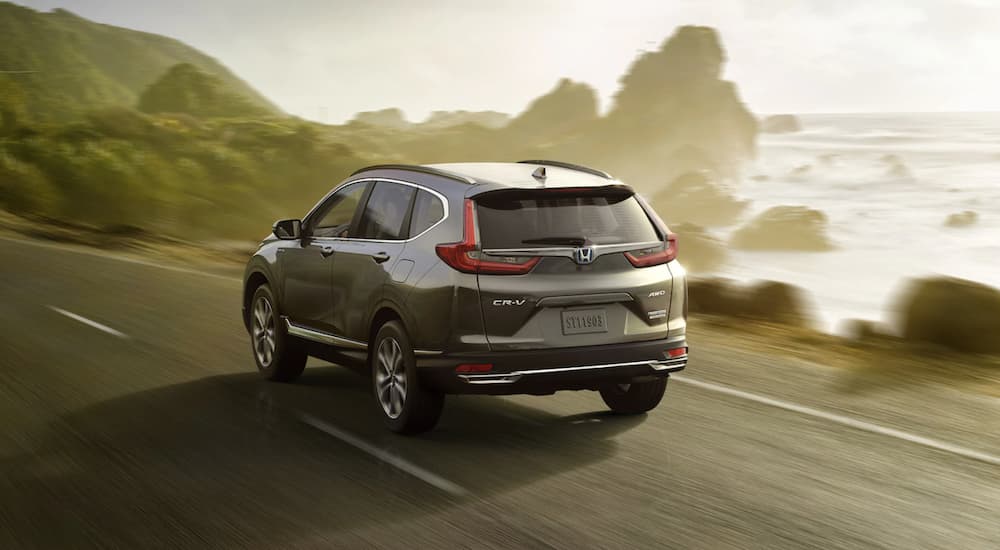 A grey 2021 Honda CR-V is driving past a lake in the fog after leaving a Honda dealer.