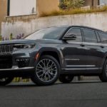 A black 2021 Jeep Grand Cherokee L is parked in front of a modern house after leaving a Jeep dealership.