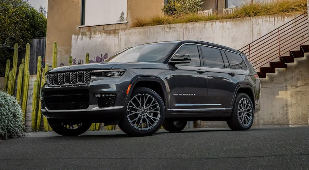 A black 2021 Jeep Grand Cherokee L is parked in front of a modern house after leaving a Jeep dealership.