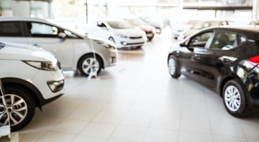 A blurred image shows a car dealership with a room full of cars.