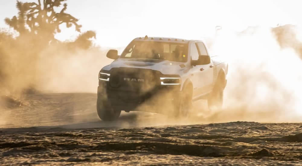 A white 2021 Ram 2500 is driving through a dusty desert.