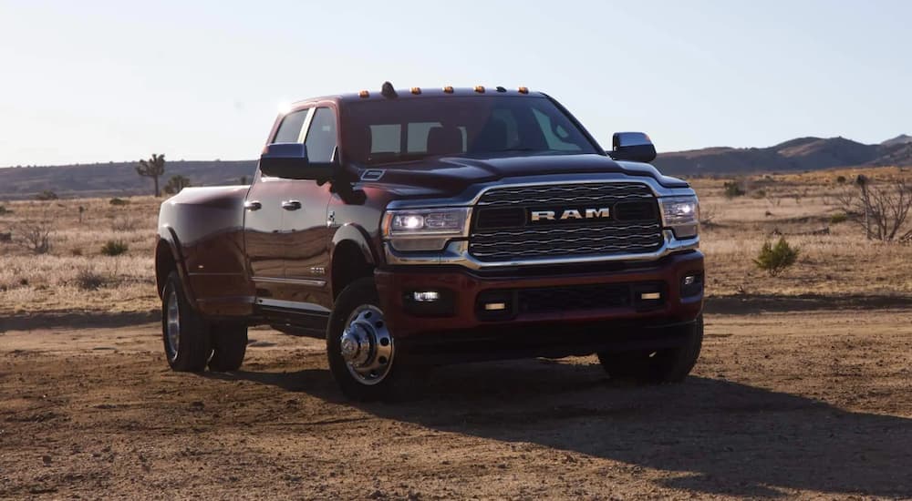 A maroon 2021 Ram 3500 is parked on a dirt field in the afternoon.