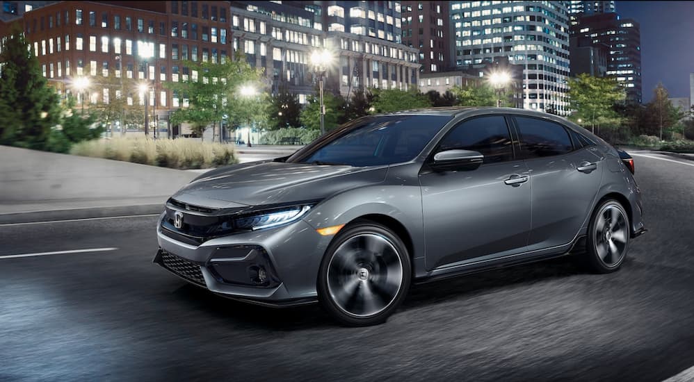 A silver 2021 Honda Civic is driving through a city at night.