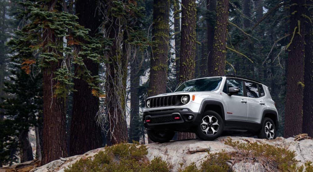 A white 2020 used Jeep Renegade Trailhawk is parked on a rock in the woods after leaving a pre-owned Jeep dealer.