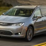 A tan 2017 used Chrysler Pacifica is driving down a two way road.