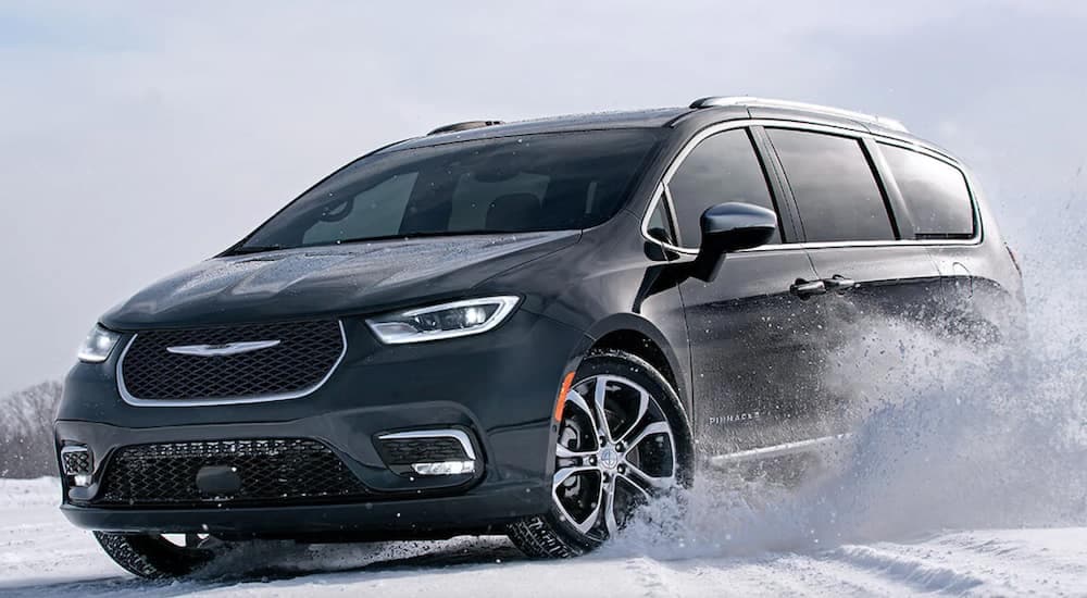 A black 2021 used Chrysler Pacifica is driving through snow.