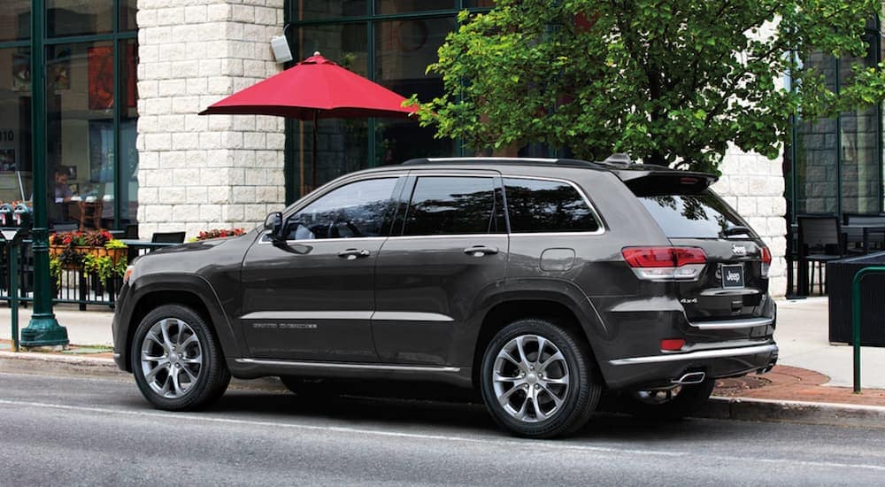 A grey 2020 Jeep Grand Cherokee Summit is parked outside of a city building after leaving a used SUV dealer.