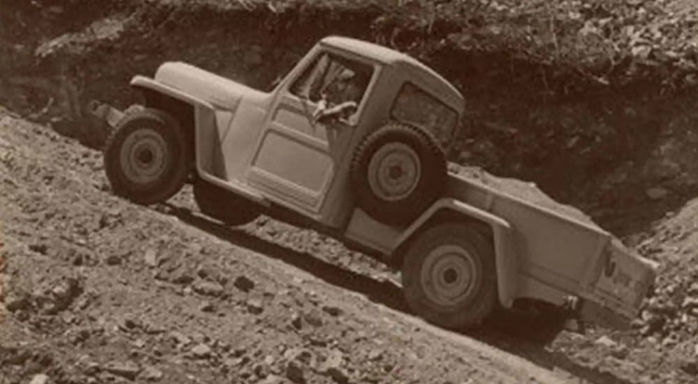 A 1947 Jeep Willys Overland is driving up a dirt hill.