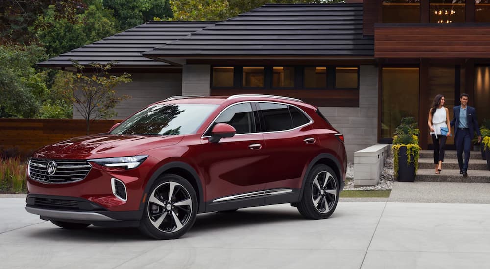 A red 2021 Buick Envision is parked in front of a modern house.