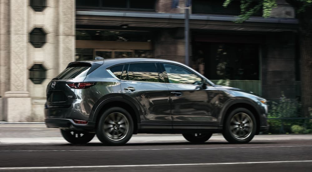 A green 2021 Mazda CX-5 is driving on a city street.