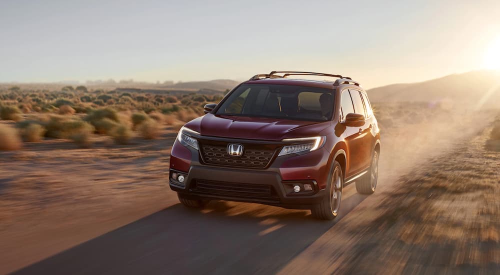 A 2021 Honda Passport AWD Elite is shown from the front driving through a desert.