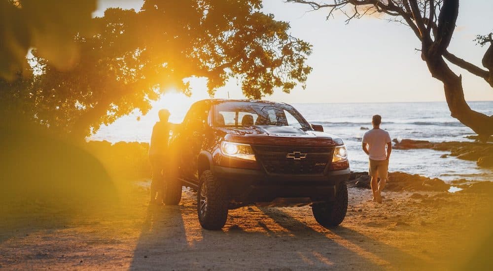 A red 2021 Chevy Colorado ZR2 is shown parked next to people on a beach.