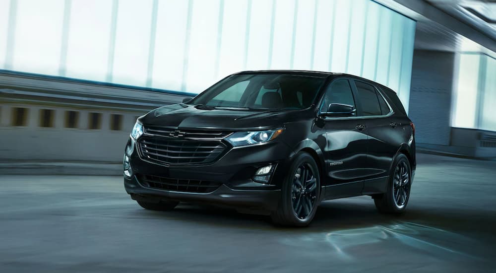 A black 2021 Chevy Equinox is driving after winning a 2021 Chevy Equinox vs 2021 Kia Sportage comparison.