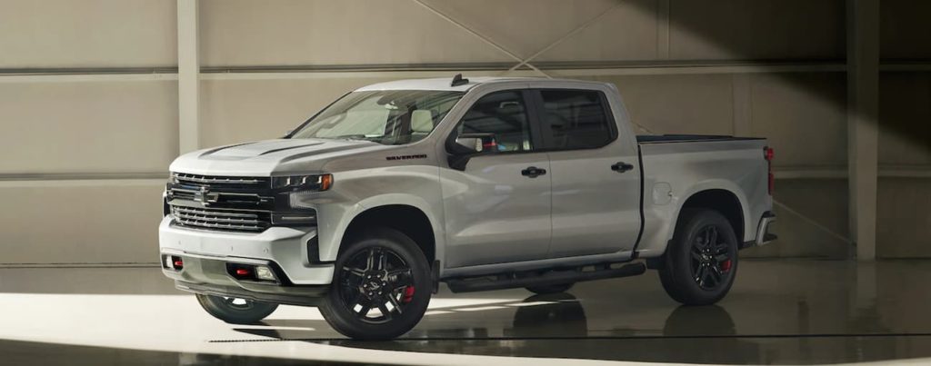 A silver 2021 Chevy Silverado 1500 is parked in a modern gallery after winning a 2021 Chevy Silverado vs 2021 Ford F-150 comparison.
