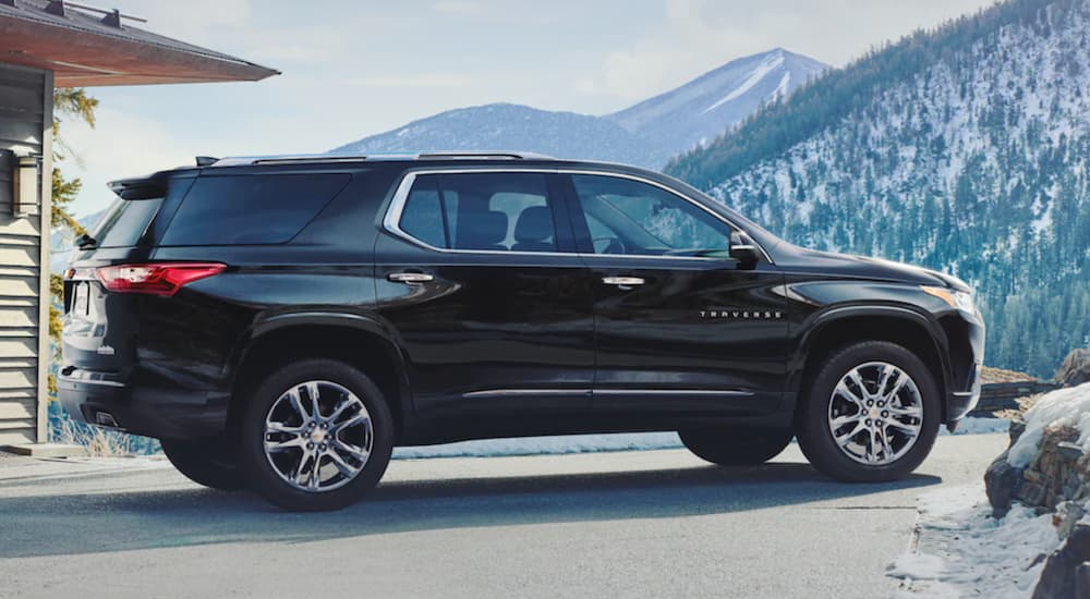 A black 2021 Chevy Traverse is parked next to a modern house in the mountains.