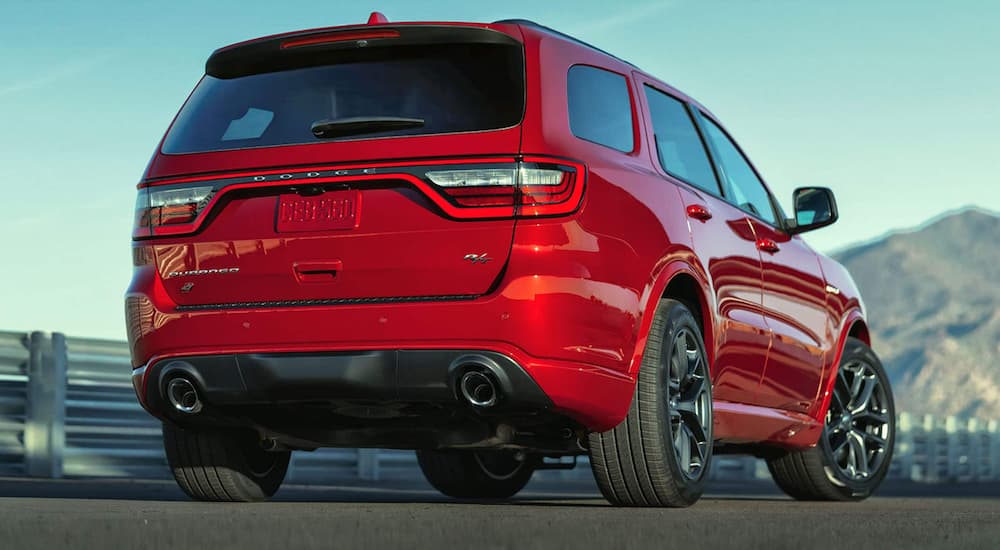 A red 2021 Dodge Durango is shown from the back parked in front of the mountains on a highway.