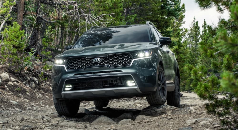 A green 2021 Kia Sorento is shown off-roading in the mountains.