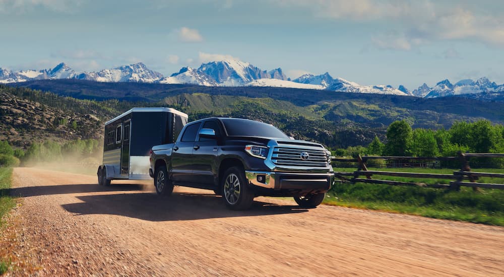 A black 2021 Toyota Tundra 1794 Edition CrewMax is shown towing a trailer down a dirt path.