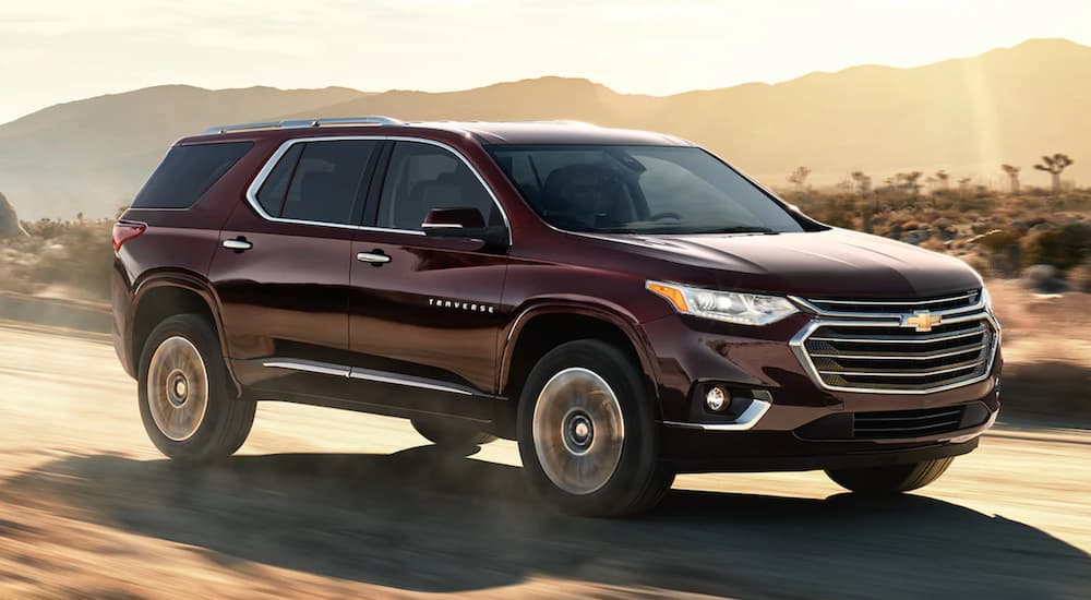 A maroon 2021 Chevy Traverse is driving down a desert road.