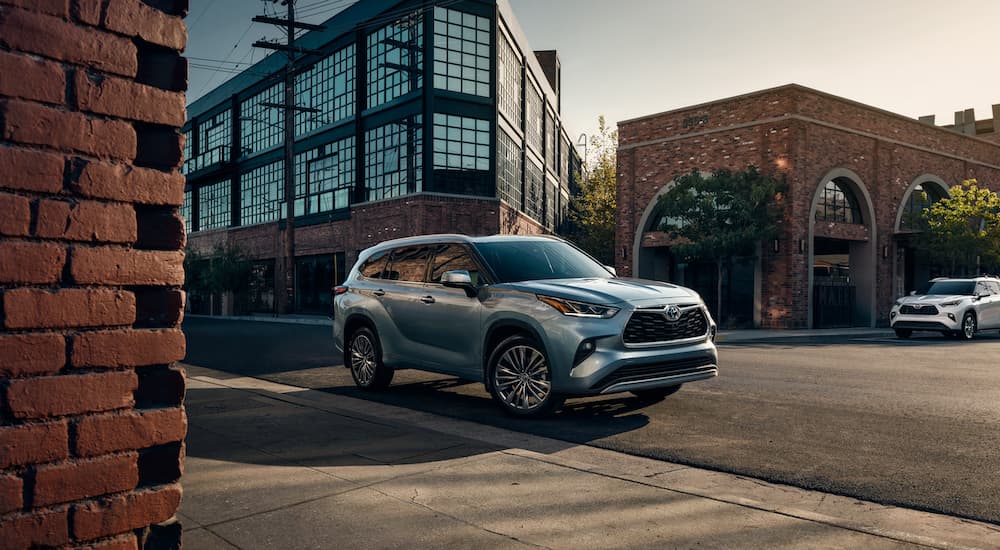 A grey 2021 Toyota Highlander is driving through a city after winning a 2021 Toyota Highlander vs 2021 Chevy Traverse comparison.
