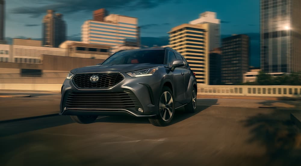 A grey 2021 Toyota Highlander is driving through a city.