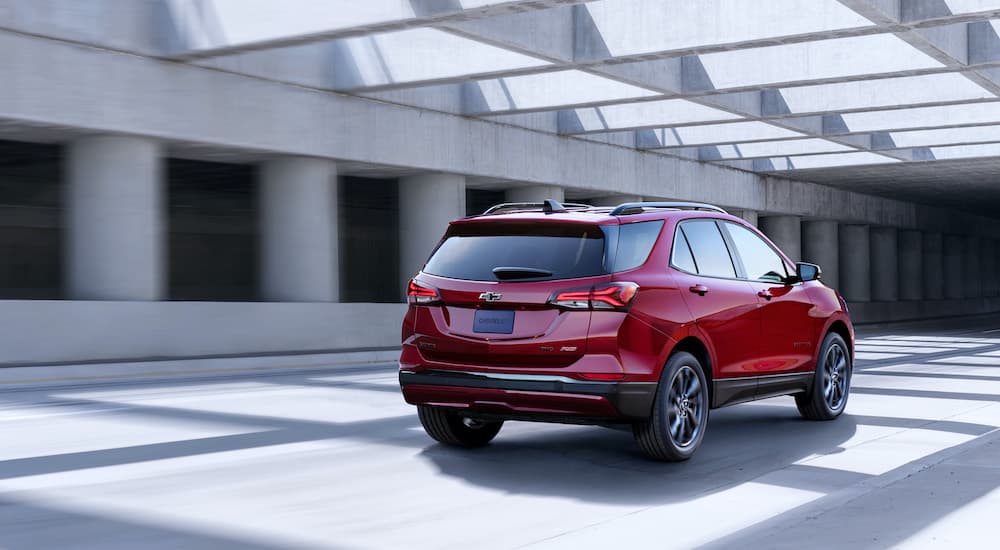 A red 2022 Chevy Equinox is shown from the rear driving on a modern road. 