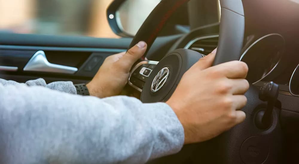 A close up shows hands on the steering wheel of a 2022 Volkswagen Golf GTI.